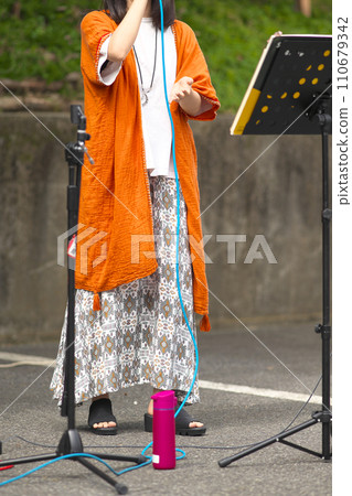 Woman singing at an outdoor event Woman singing at an outdoor event 110679342