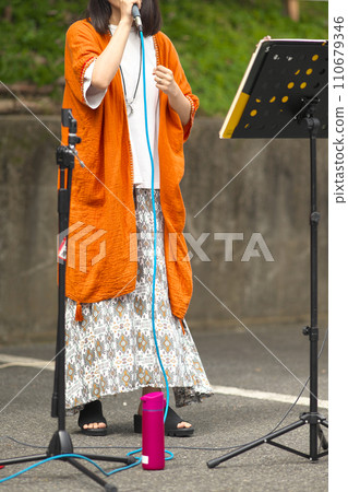 Woman singing at an outdoor event 110679346