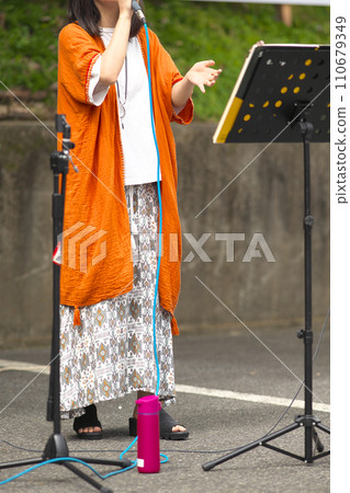Woman singing at an outdoor event Woman singing at an outdoor event 110679349