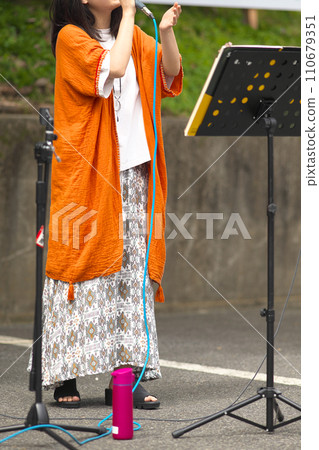 Woman singing at an outdoor event Woman singing at an outdoor event 110679351