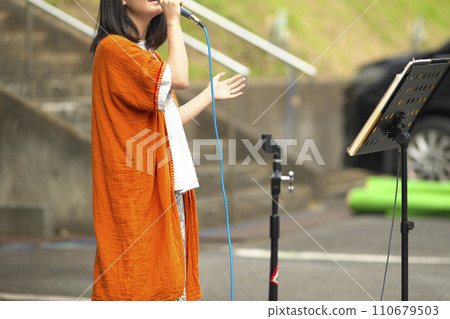 Woman singing at an outdoor event Woman singing at an outdoor event 110679503