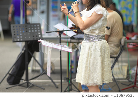 Woman singing at an outdoor event Woman singing at an outdoor event 110679523