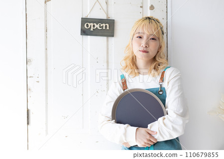 一名年輕女子站在門前準備開門營業 一名年輕女子站在門前準備開門營業 110679855