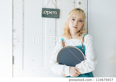 A young woman stands in front of the door preparing to open the store A young woman stands in front of the door preparing to open the store 110679857