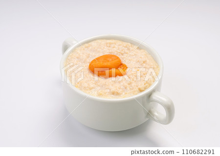 Breakfast. Oatmeal porridge with apricot on a white plate and a white background Breakfast. Oatmeal porridge with apricot on a white plate and a white background 110682291