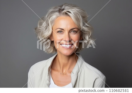 Portrait of a happy senior woman smiling at the camera over grey background. 110682581