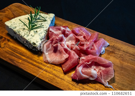 Blue cheese and prosciutto on cutting board Blue cheese and prosciutto on cutting board 110682651