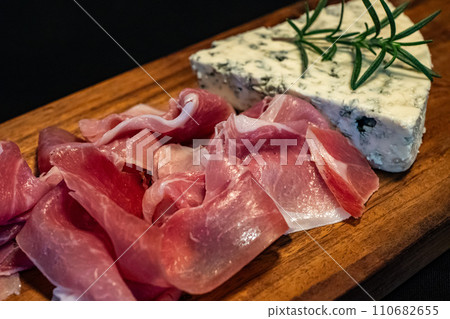 Blue cheese and prosciutto on cutting board 110682655