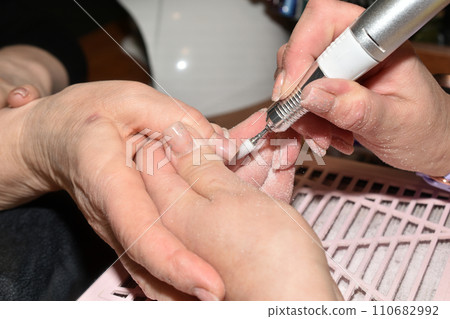 The manicurist uses a router to trim the edges of the nail. The manicurist uses a router to trim the edges of the nail. 110682992