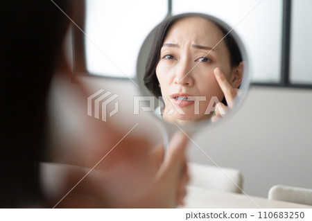 一個女人看著鏡子，想知道她的皮膚狀況 110683250