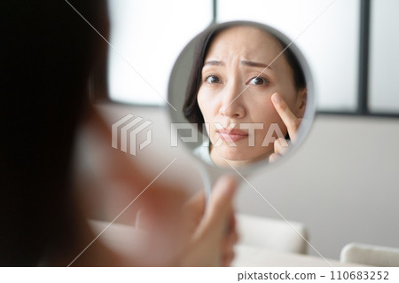 A woman looking at the mirror and wondering about her skin condition 110683252