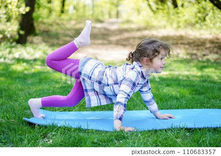 Child Girl doing yoga exercises in the park, healthy lifestyle 110683357