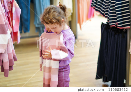 Cute child girl chooses dress in shop store with clothes 110683412
