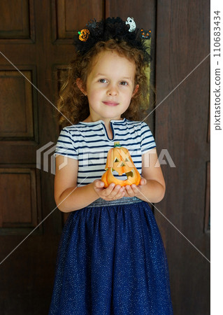 happy child girl with pumpkin outdoors in halloween, black background 110683434