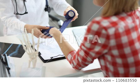 Physiotherapist man put bandage on female patient hand, post traumatic rehabilitation Physiotherapist man put bandage on female patient hand, post traumatic rehabilitation 110683550