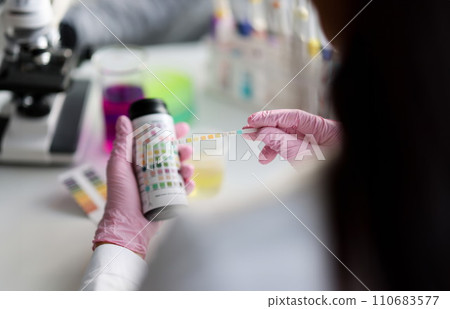 Clever scientist hold litmus test paper for soil analysis, papers show acidity Clever scientist hold litmus test paper for soil analysis, papers show acidity 110683577