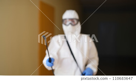 Medical worker in protective clothing and medical mask cleans and disinfects room 110683647