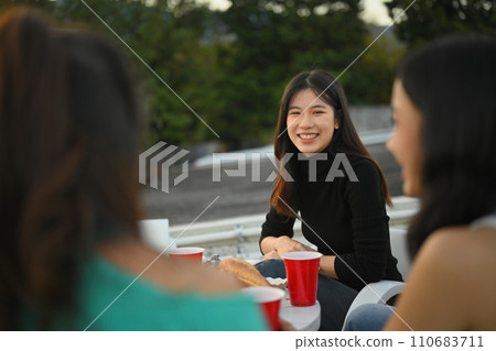 Attractive young woman talking with friends during rooftop party. Attractive young woman talking with friends during rooftop party. 110683711