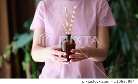 Woman holds jar with an aromatic diffuser of homemade fragrance in hands Woman holds jar with an aromatic diffuser of homemade fragrance in hands 110683994