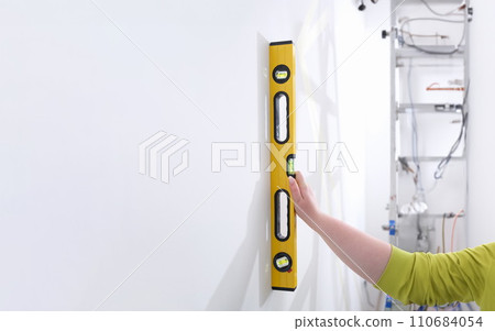 Builder hand with building level measures wall Builder hand with building level measures wall 110684054
