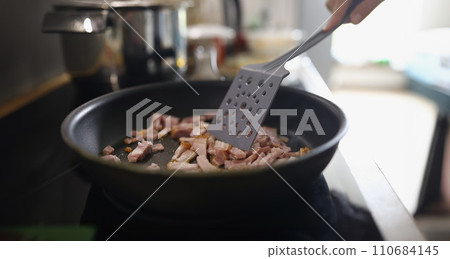 Chef stir ham or bacon slices on hot pan, person frying meat for breakfast or dinner Chef stir ham or bacon slices on hot pan, person frying meat for breakfast or dinner 110684145