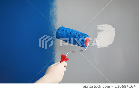 Worker with roller tool ready to paint walls, cover in blue colour 110684164