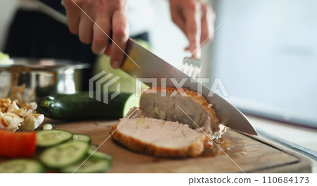 Person cutting homemade ham, delicious aromatic meat with garlic pieces 110684173