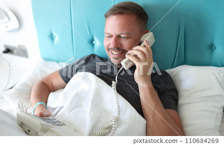 Smiling man calling on reception in hotel, want to order lunch in room 110684269
