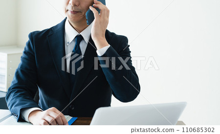 商人一邊看電腦一邊用智慧型手機交談 110685302