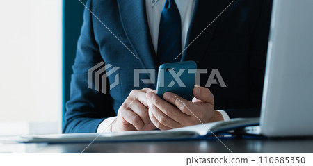 Hand of a businessman sending an email with a smartphone Hand of a businessman sending an email with a smartphone 110685350