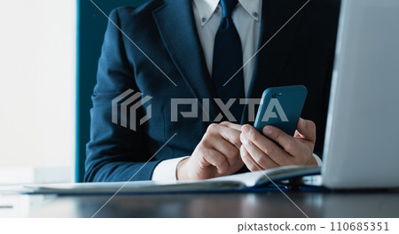 Hand of a businessman sending an email with a smartphone Hand of a businessman sending an email with a smartphone 110685351
