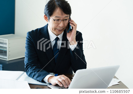 商人一邊看電腦一邊用智慧型手機交談 110685507