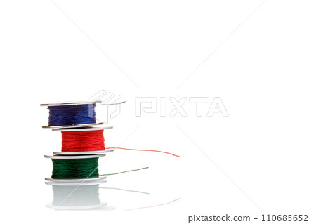 spools of thread in blue, red, green colors on a white background 110685652