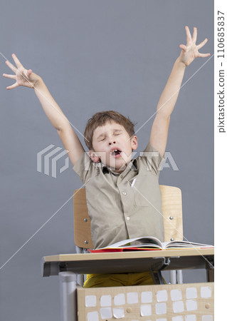 The child yawns in the classroom. Elementary school student wants to sleep in class. The child yawns in the classroom. Elementary school student wants to sleep in class. 110685837