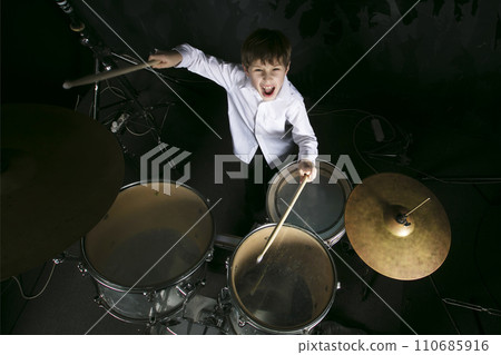 The child plays the drums. Boy musician behind a drum kit. The child plays the drums. Boy musician behind a drum kit. 110685916