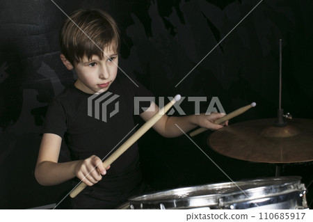 The child behind the drum. A boy with drumsticks behind a drum kit. The child behind the drum. A boy with drumsticks behind a drum kit. 110685917