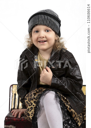 Little beautiful girl. A cheerful child sits on an accordion. Beautiful five year old baby. Little beautiful girl. A cheerful child sits on an accordion. Beautiful five year old baby. 110686614