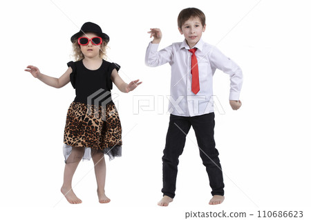 Funny kids dancing on a white background. Little girl in a hat and a boy in a tie are dancing. Ballroom dancing. Dance couple Funny kids dancing on a white background. Little girl in a hat and a boy in a tie are dancing. Ballroom dancing. Dance couple 110686623