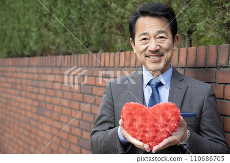 中間商人微笑著拿著一顆紅心 中間商人微笑著拿著一顆紅心 110686705