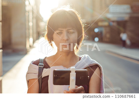 A girl in the city films herself on her phone A girl in the city films herself on her phone 110687661