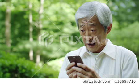 An anxious old man looking at his smartphone 110687716