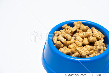 A treat for cats and kittens is a fish-shaped catnip cookie in a blue bowl, copy space for text. 110688135