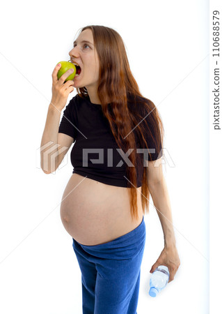 Pregnant woman propose apple for her belly copy space. Beautiful expectant lady having fresh snack, gray studio background. Healthy nutrition and pregnancy concept, copy space Pregnant woman propose apple for her belly copy space. Beautiful expectant lady having fresh snack, gray studio background. Healthy nutrition and pregnancy concept, copy space 110688579