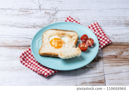 Valentine's Day breakfast with egg with tomatoes, heart shaped and toast bread on wooden table. 110688968