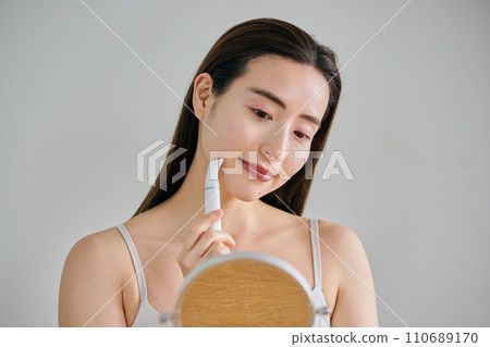一名30多歲的女士用電動刮鬍刀刮臉 一名30多歲的女士用電動刮鬍刀刮臉 110689170