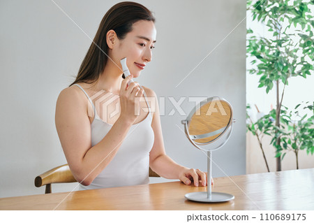 A woman in her 30s shaving her face with an electric shaver 110689175
