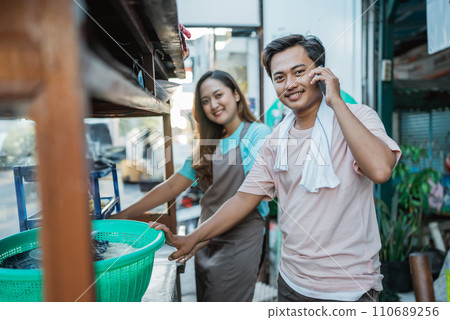 asian seller holding phone calling behind food cart asian seller holding phone calling behind food cart 110689256