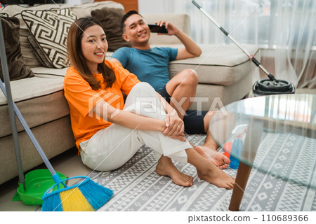 asian couple sitting on rug after housekeeping asian couple sitting on rug after housekeeping 110689366