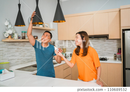 asian female helping husband changing light bulb 110689532