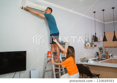 asian woman helping partner fixing airconditioner asian woman helping partner fixing airconditioner 110689563